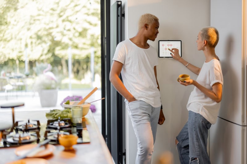 Man and woman standing in front of thermostat.